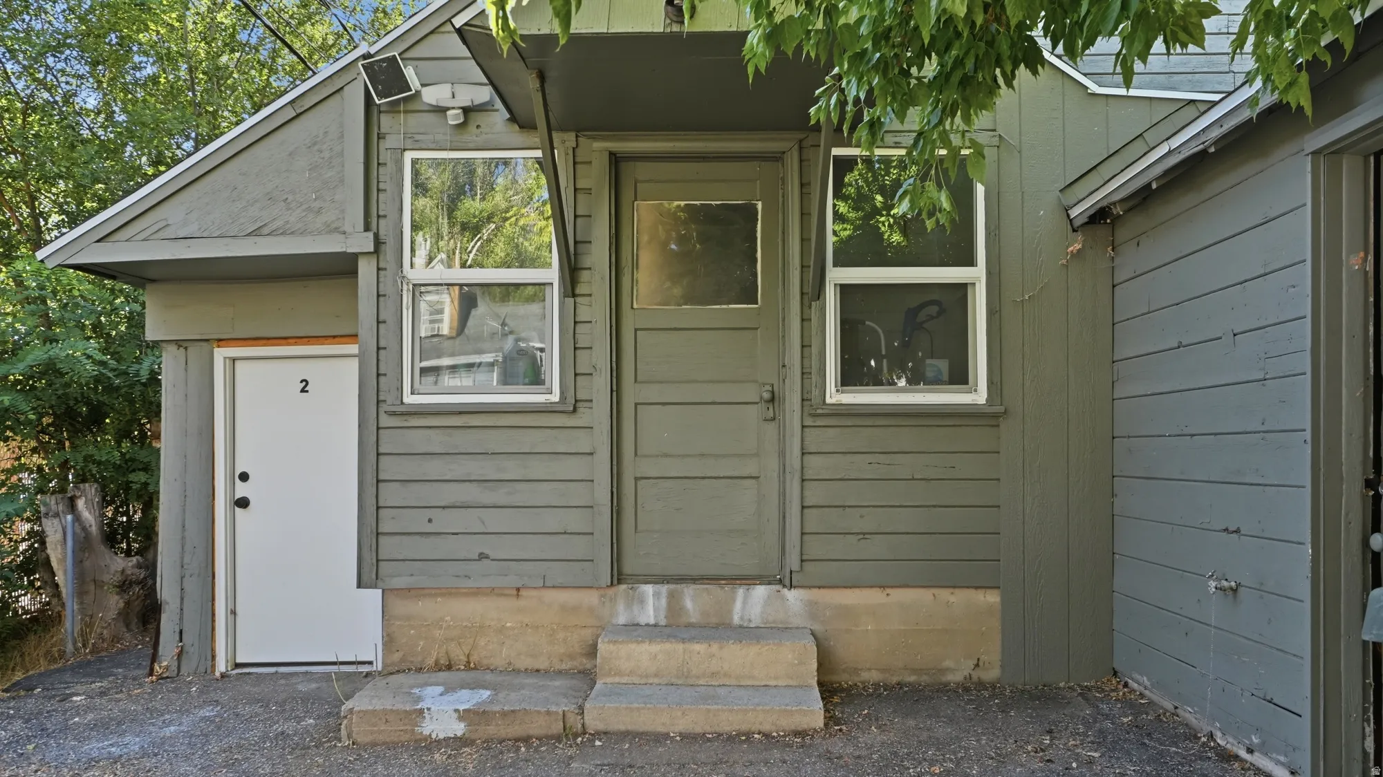 Exterior siding with a neutral finish, multiple windows, and a concrete entry