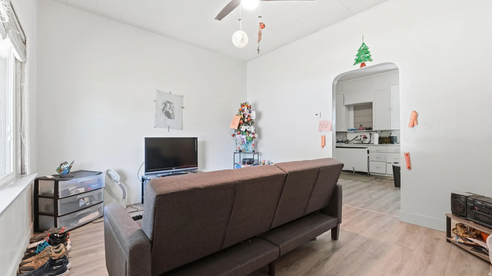 Open-concept living area featuring wood-finish flooring, a dark upholstered sofa, and integrated entertainment setup with wall-mounted television