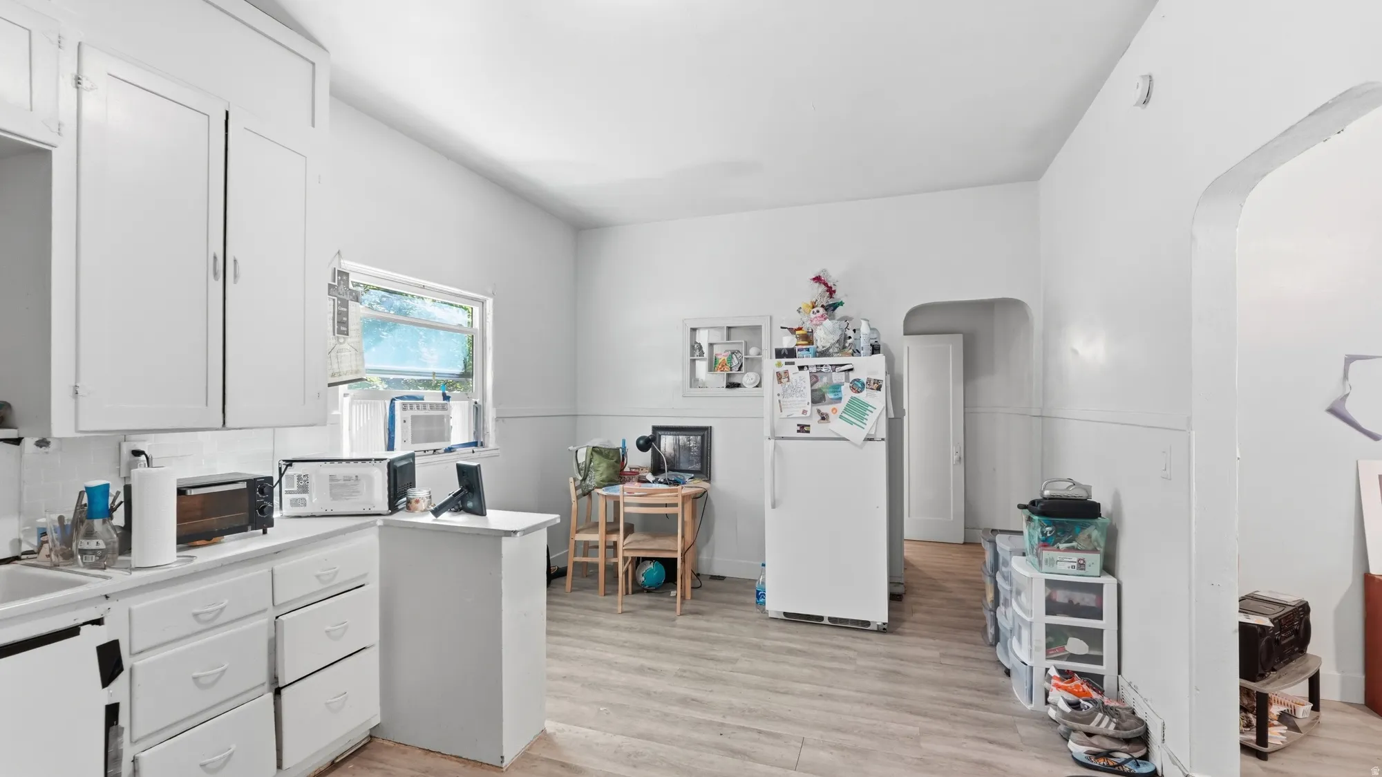 White cabinetry, light wood-finish flooring, and white appliances