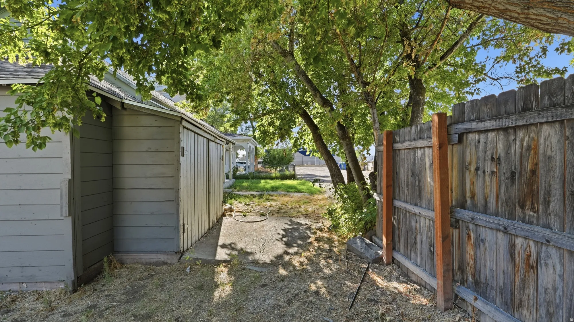 Siding structure with a sloped roof, concrete slab, and wood privacy fencing