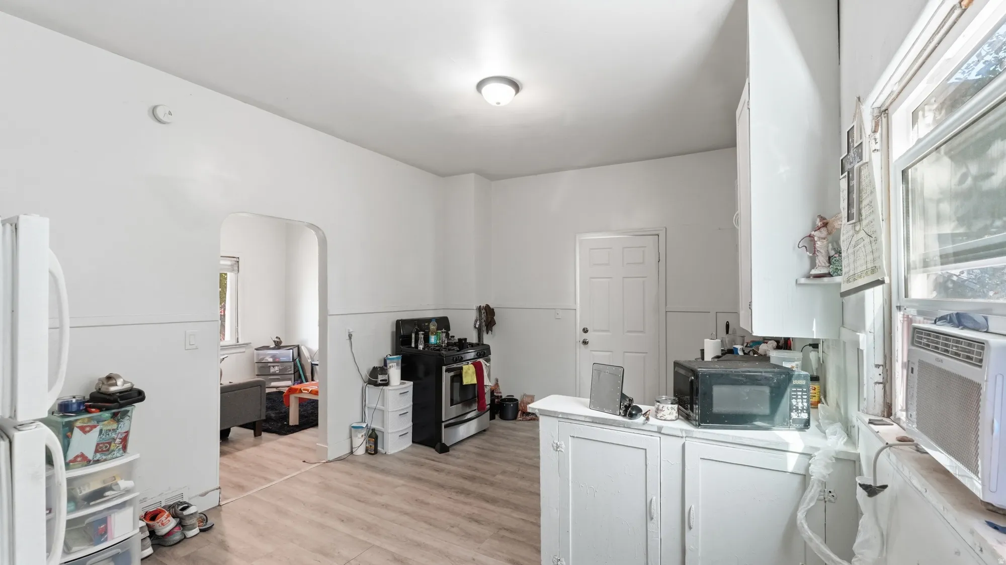 Kitchen featuring light wood-finish flooring, white cabinetry, a built-in oven range, and a window