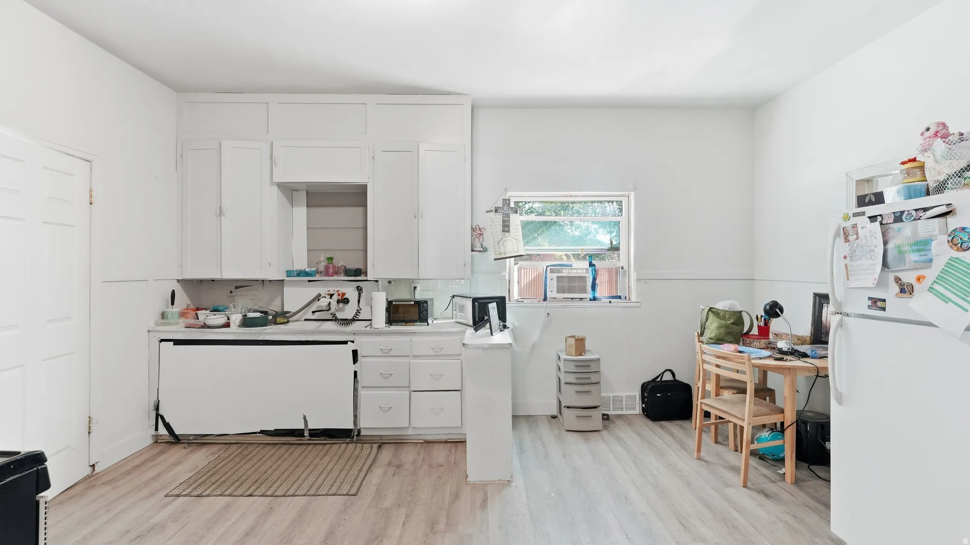 Kitchen featuring wood-finish flooring, white cabinetry, a single window, and white walls