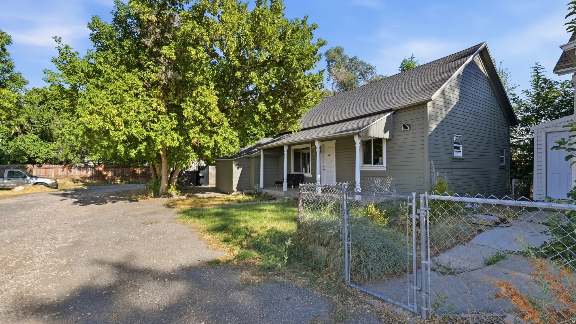 Shingle roof residence with horizontal siding, covered front porch, and a gravel parking area