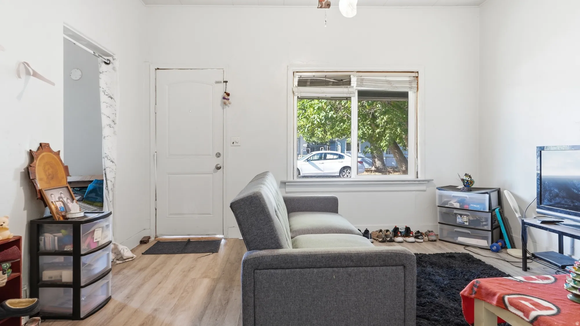 Light wood-finish flooring with white painted walls and a ceiling fan