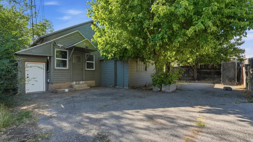 Gravel driveway leading to a residence with green siding, multiple windows, and a covered entry