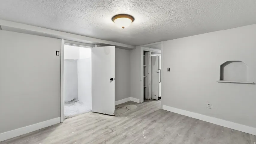 Light wood-finish flooring, ceiling-mounted light fixture, recessed wall niche, and two doorways