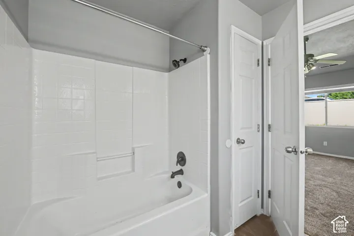 White tile shower surround with integrated tub, featuring a dark bronze shower fixture