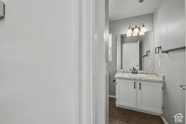 Vanity with a granite-style countertop, undermount sink, and shaker-style cabinetry