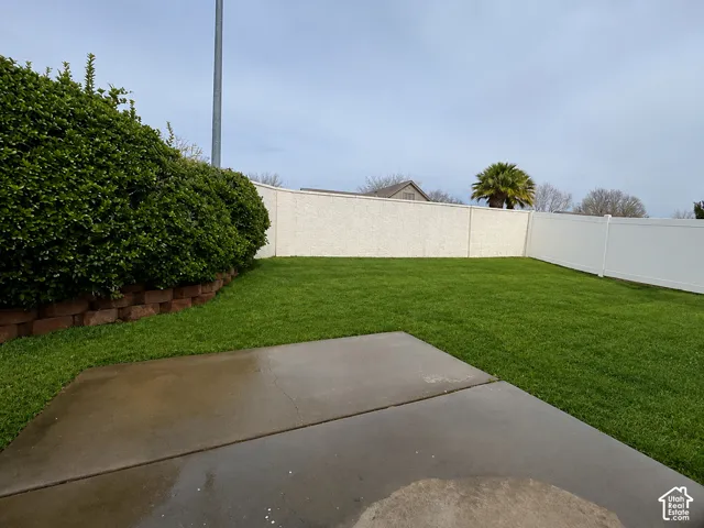Spacious backyard featuring a concrete patio, verdant lawn, and a privacy fence
