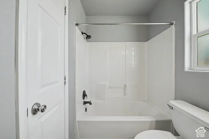 Bathtub and shower combination with white tile surround, black-finish shower fixtures, and a chrome shower rod