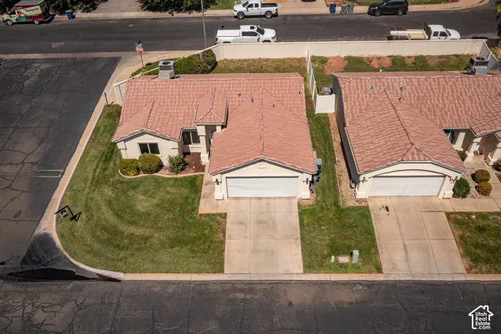 Tile roof structure, two-car garage, concrete driveway, front lawn, and foundational shrubs