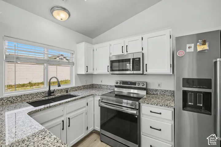 Kitchen featuring white cabinetry, granite countertops, stainless steel appliances, and a matte black faucet