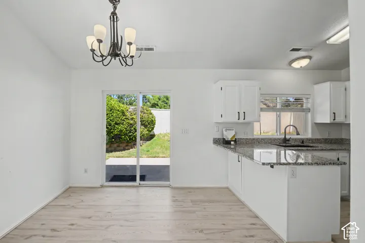 Kitchen featuring white cabinetry, granite-style countertops, and a stainless steel sink with a matte black faucet