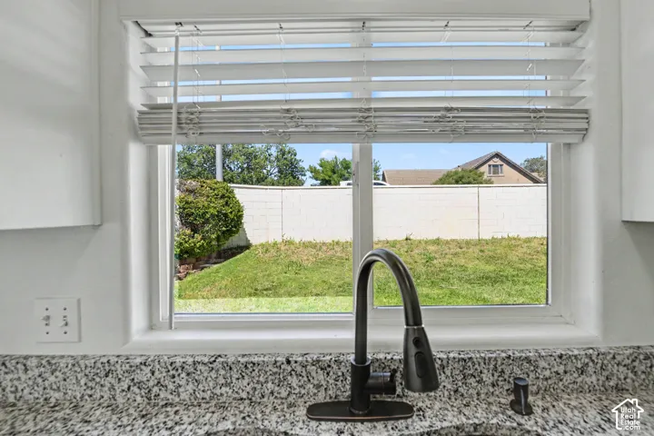 Granite-finish countertop with a gooseneck faucet and a window with horizontal blinds
