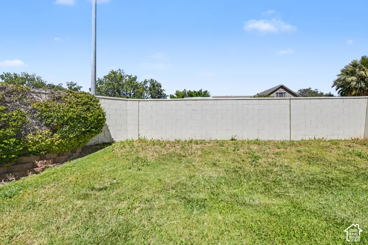 Expansive lawn area with a block privacy wall and mature landscaping