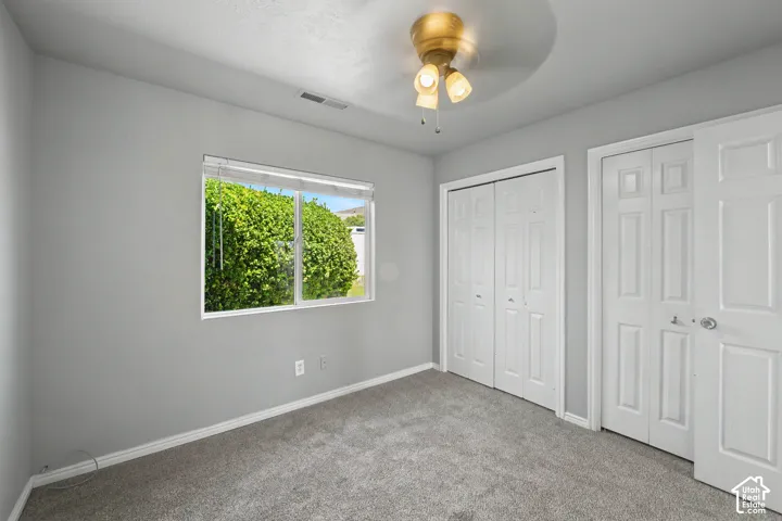 Gray carpeting with light gray walls, a window overlooking green foliage, and two white panel doors