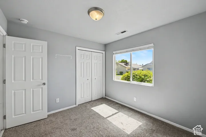 Carpeted flooring, a window with exterior scenery, a white six-panel door, and a flush mount ceiling light