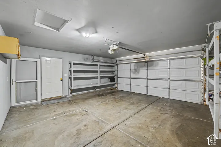 Attached two-car garage with overhead lighting and built-in shelving