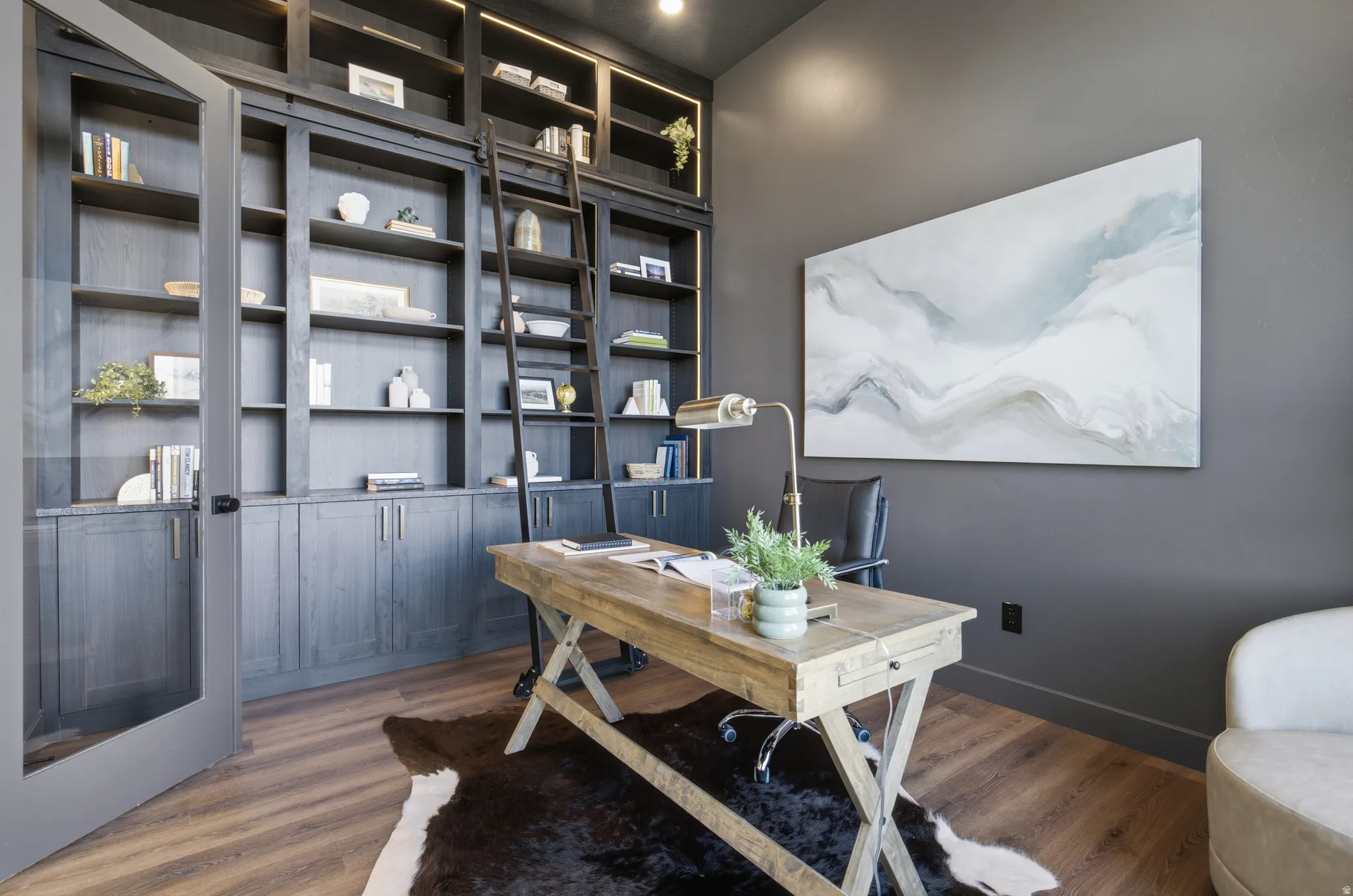 Dark-stained built-in shelving with integrated lighting and a rolling ladder