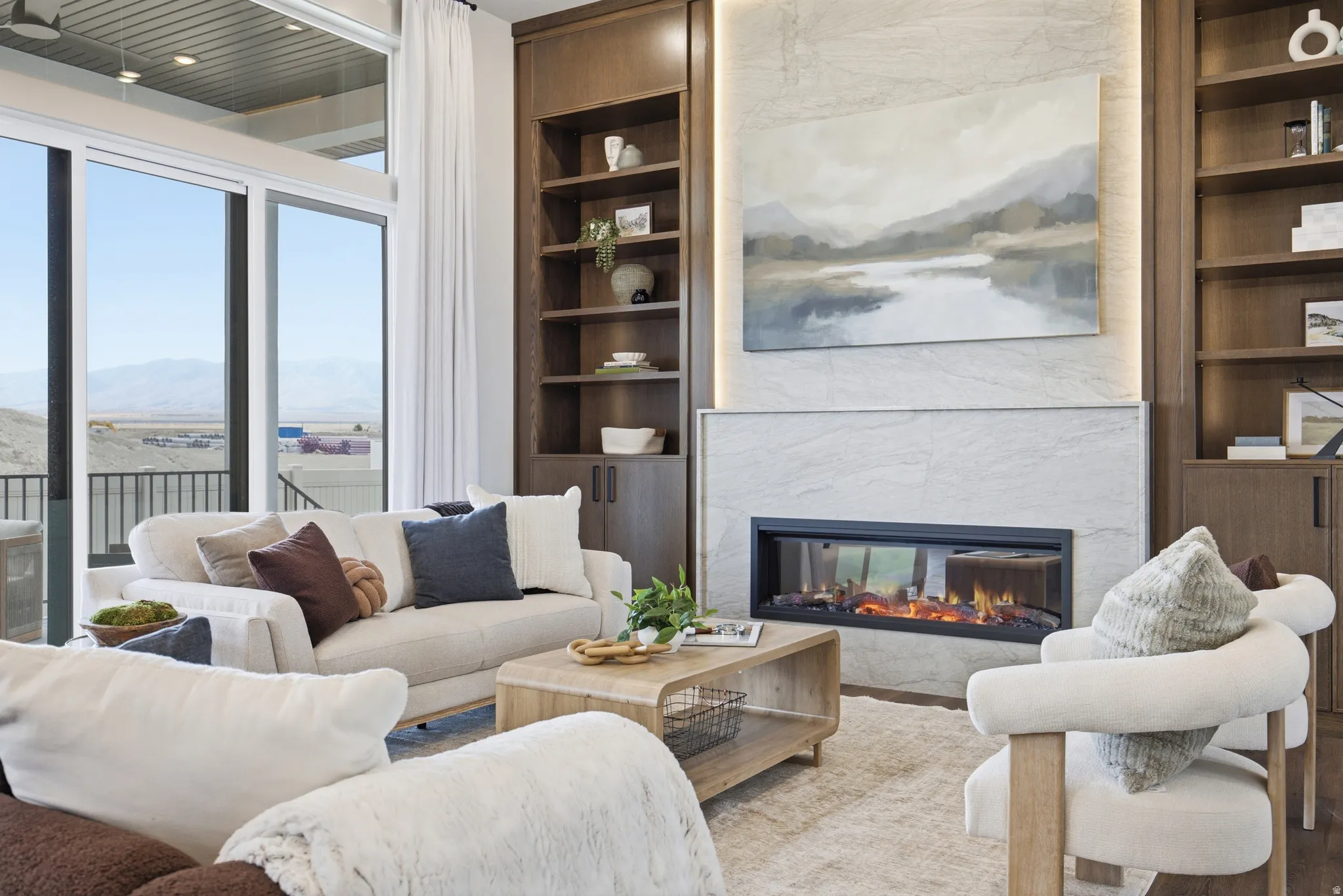 Spacious living area featuring floor-to-ceiling sliding glass doors, a modern linear fireplace with stone surround, and built-in wood-finish shelving