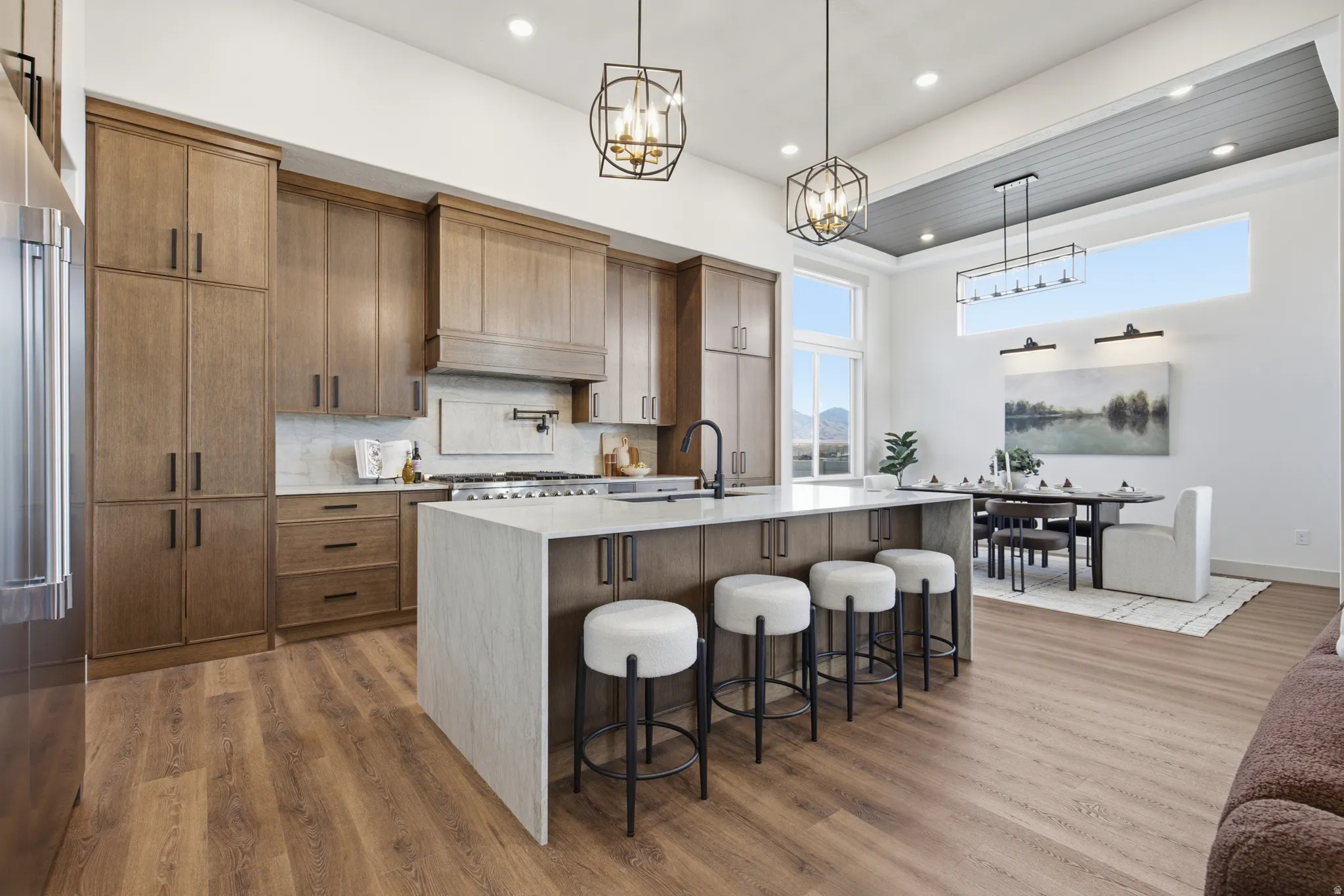 Gourmet kitchen featuring wood-finish cabinetry, quartz countertops, a large center island with seating, a stainless steel refrigerator, and a gas range