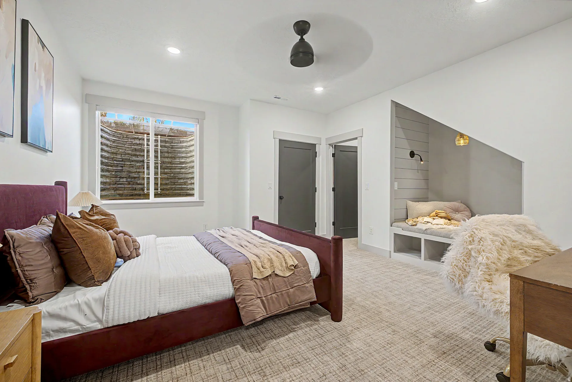 Room featuring light-toned carpet, a window with a well-curved window well, and a built-in reading nook with shiplap backing and integrated lighting