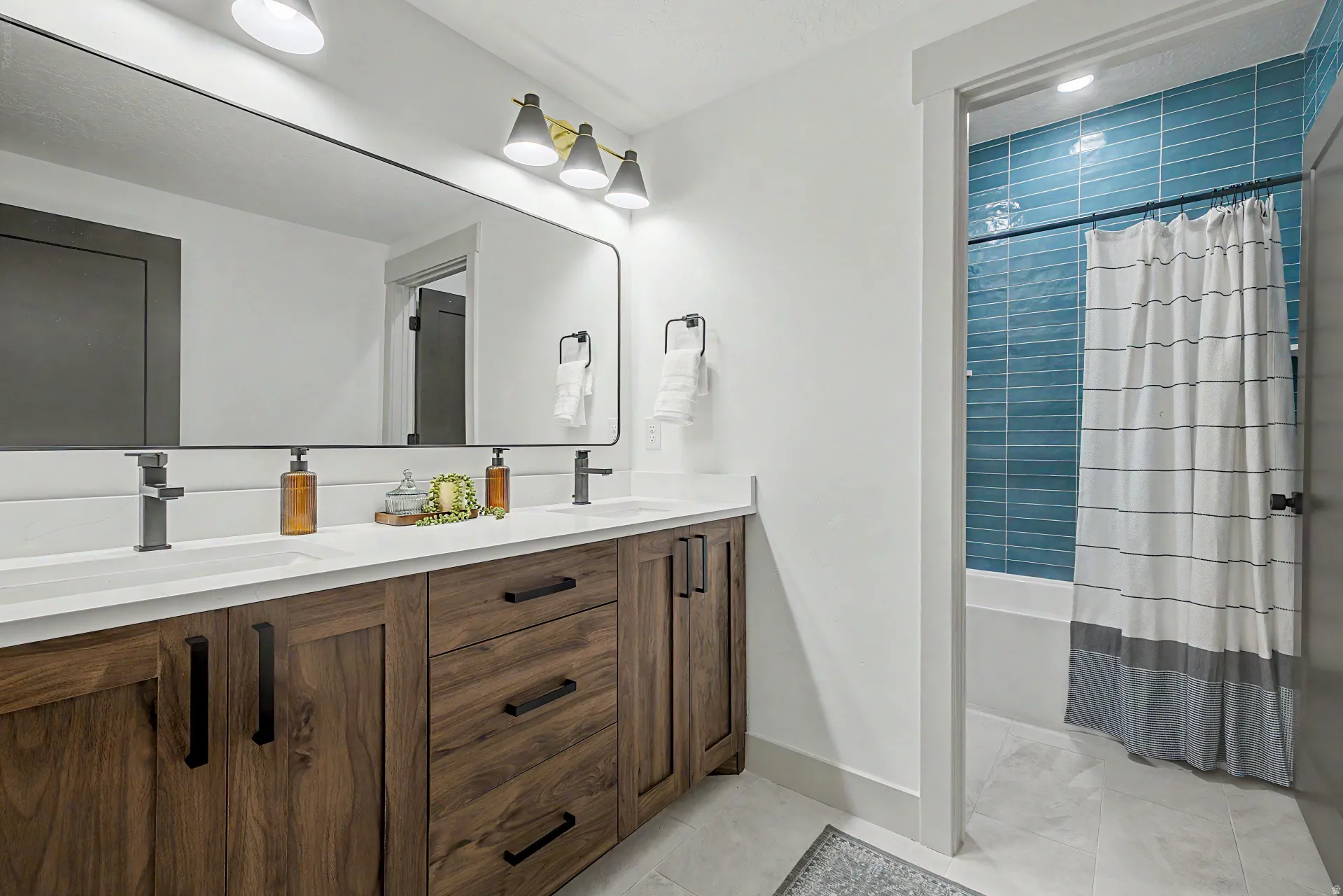 Double vanity featuring wood-finish cabinetry, white countertops, and matte black fixtures