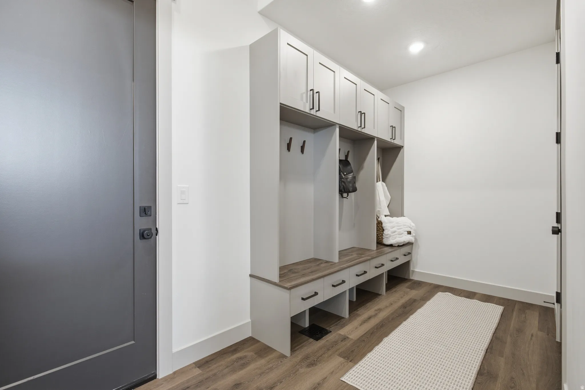 Entryway with wood-finish flooring featuring a custom built-in bench with integrated storage and overhead cabinetry