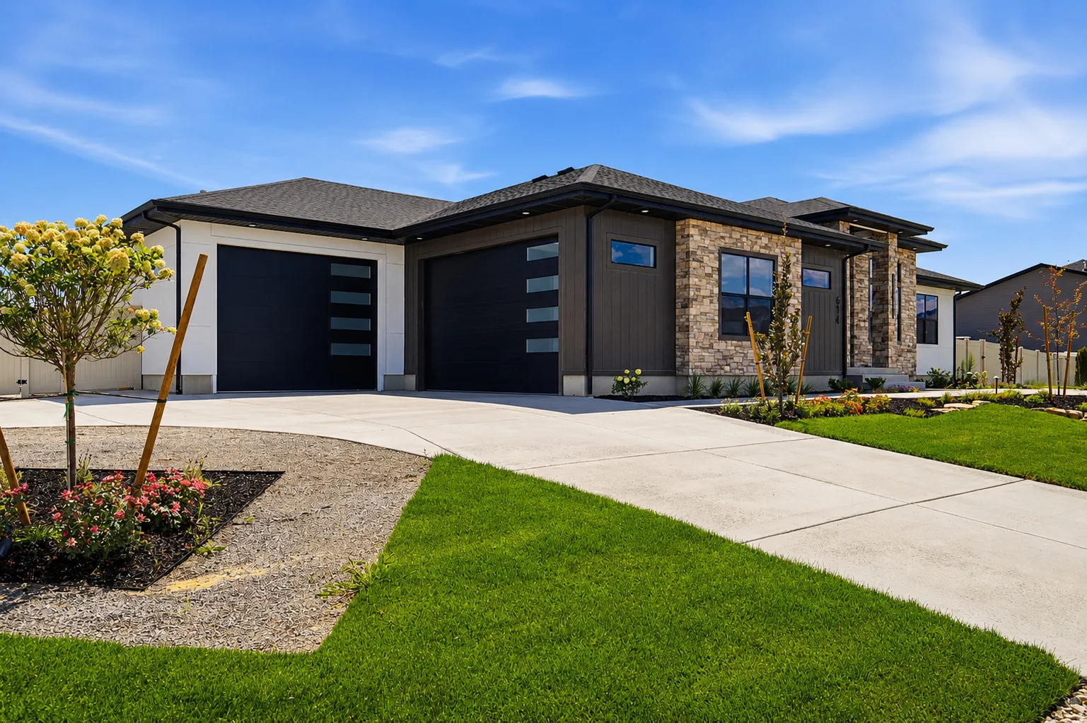 Contemporary single-story residence showcasing a multi-textured facade with stone accents, dark vertical siding, and crisp white panels