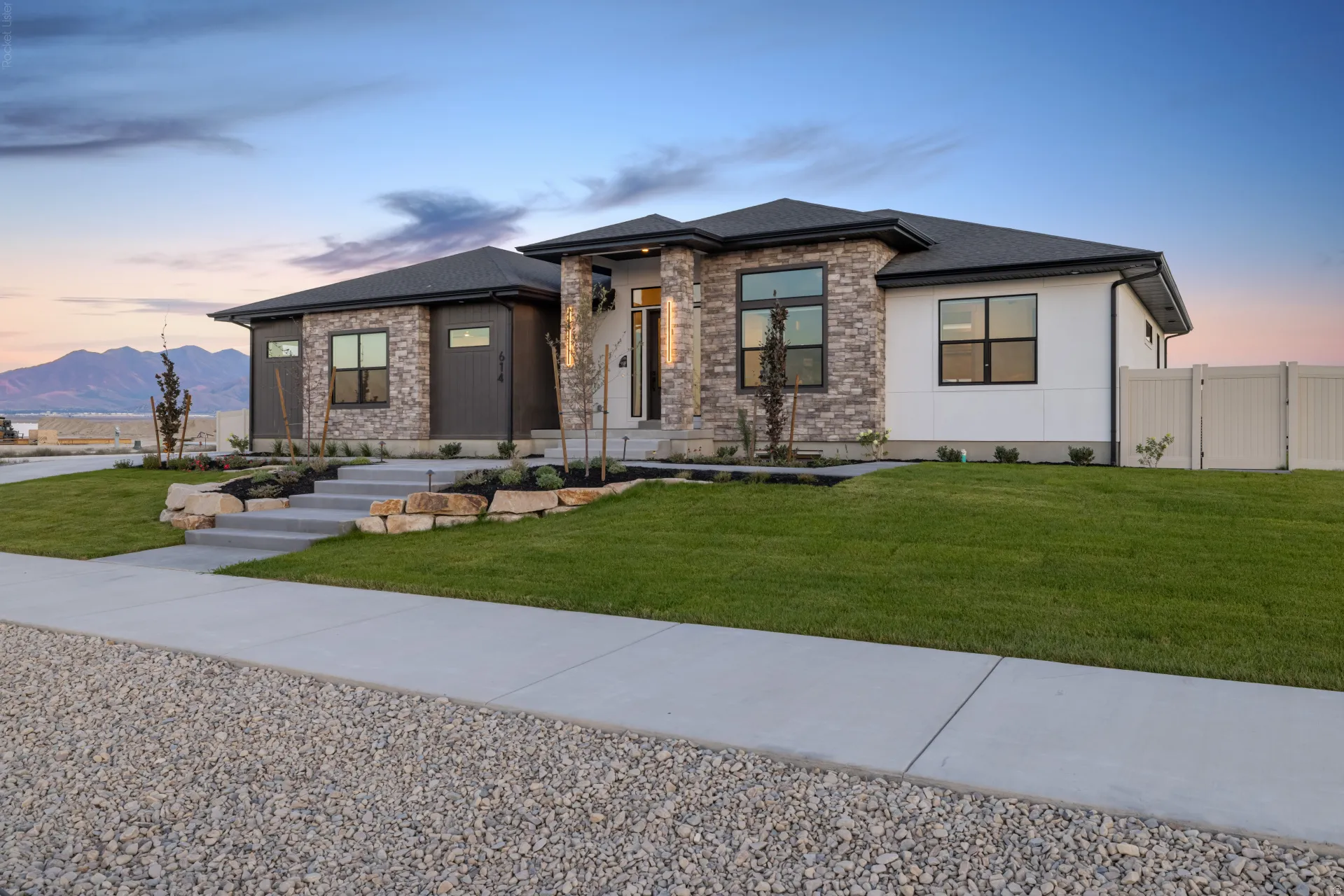 Contemporary-style residence featuring a stone and stucco exterior with dark trim windows