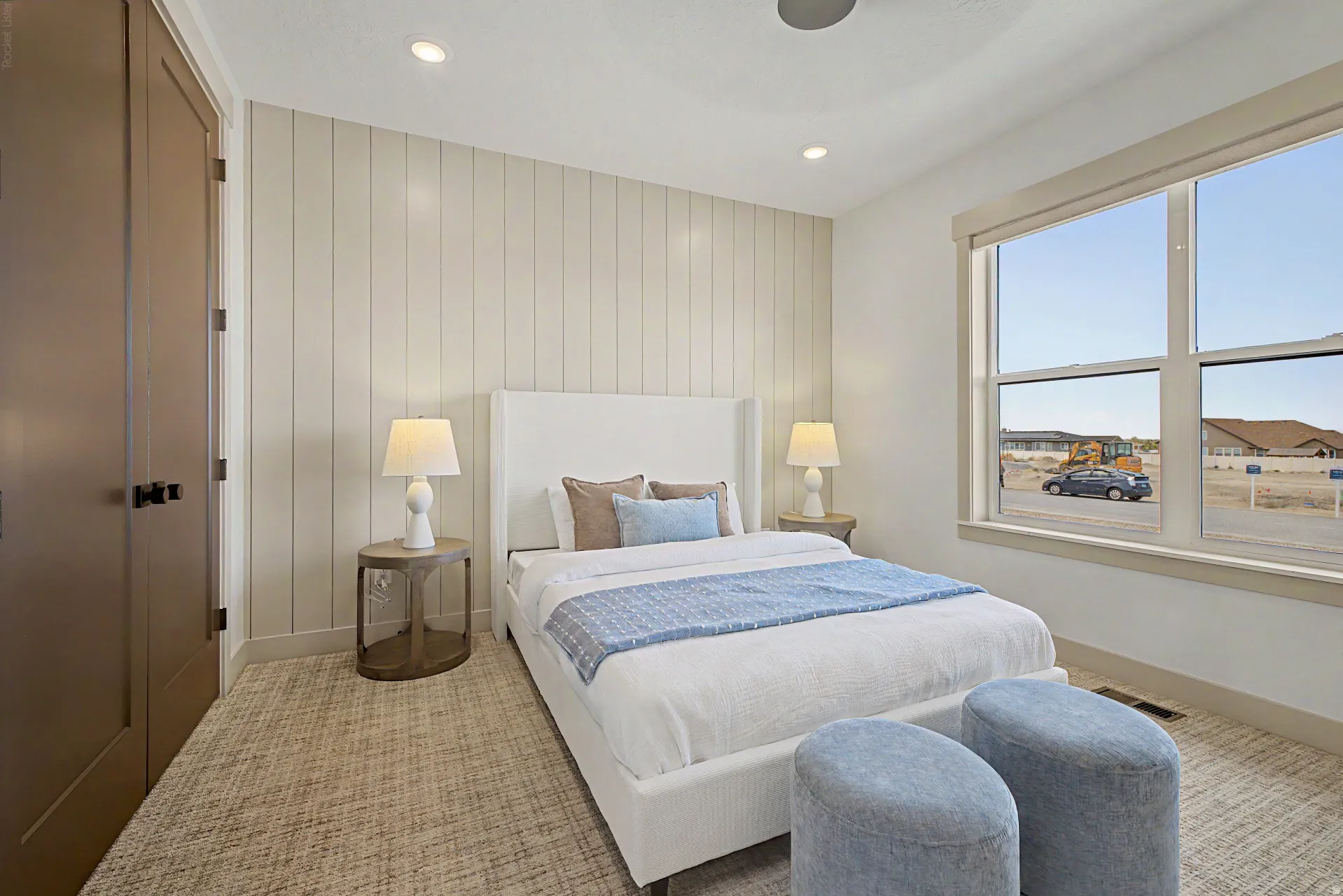 Bedroom featuring a prominent window, neutral-toned plank accent wall, and patterned carpeting