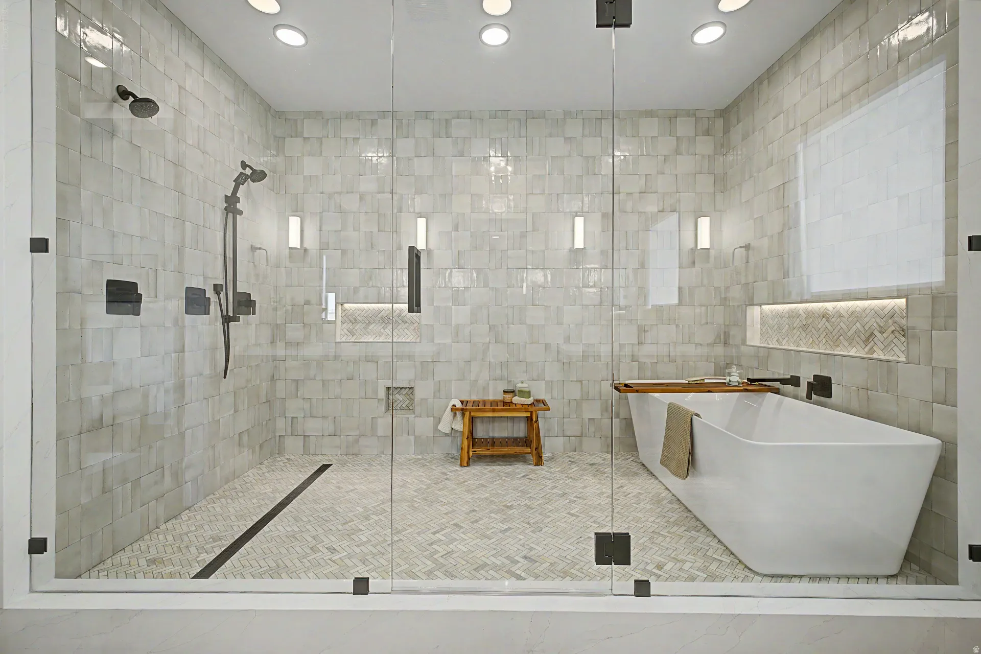 Spacious bathroom featuring a frameless glass shower enclosure, freestanding soaking tub, recessed lighting, matte black fixtures, and light-toned tile work throughout