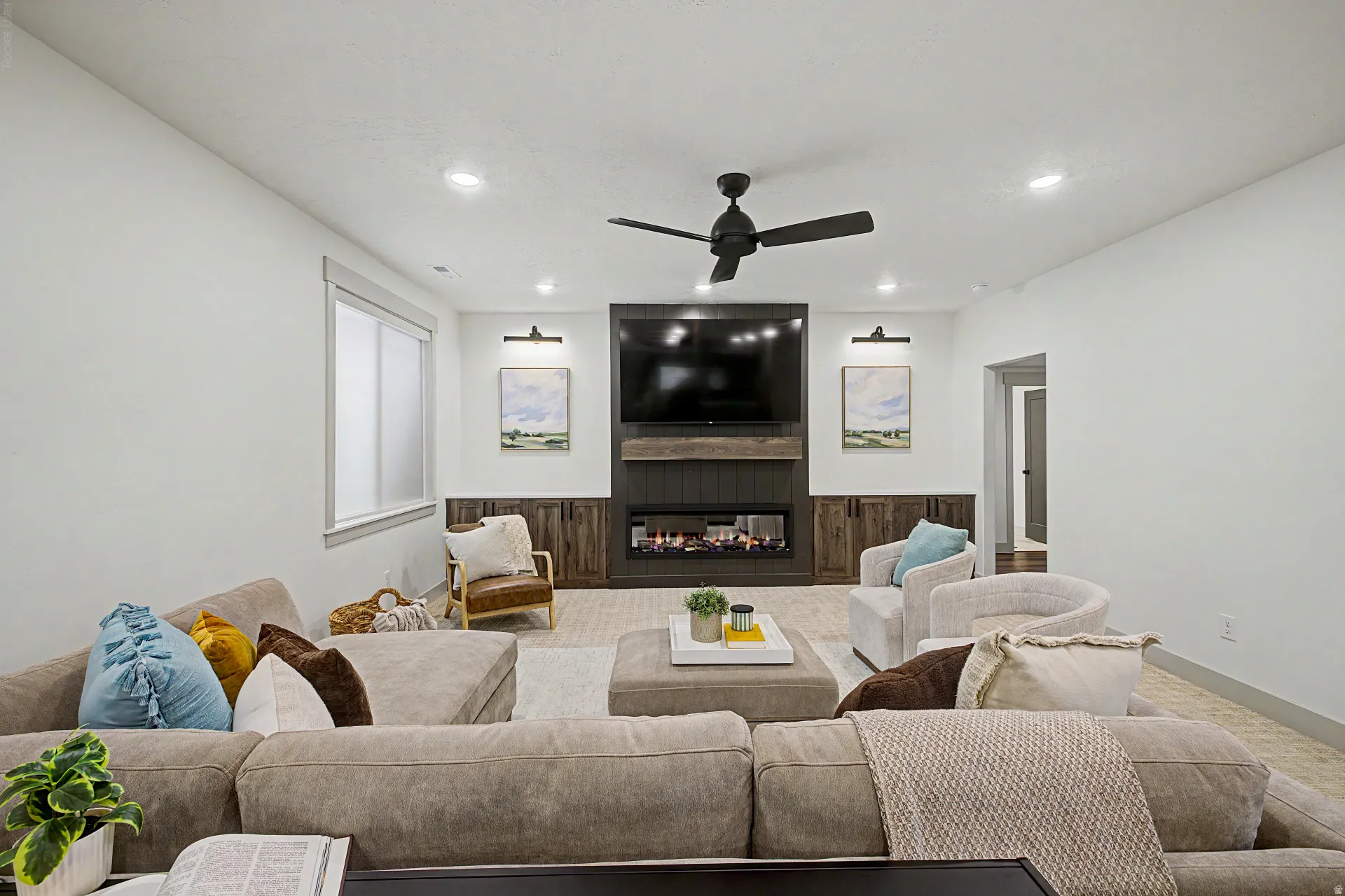 Living area featuring a contemporary fireplace with a dark wood-paneled surround, integrated media center, recessed lighting, and a ceiling fan