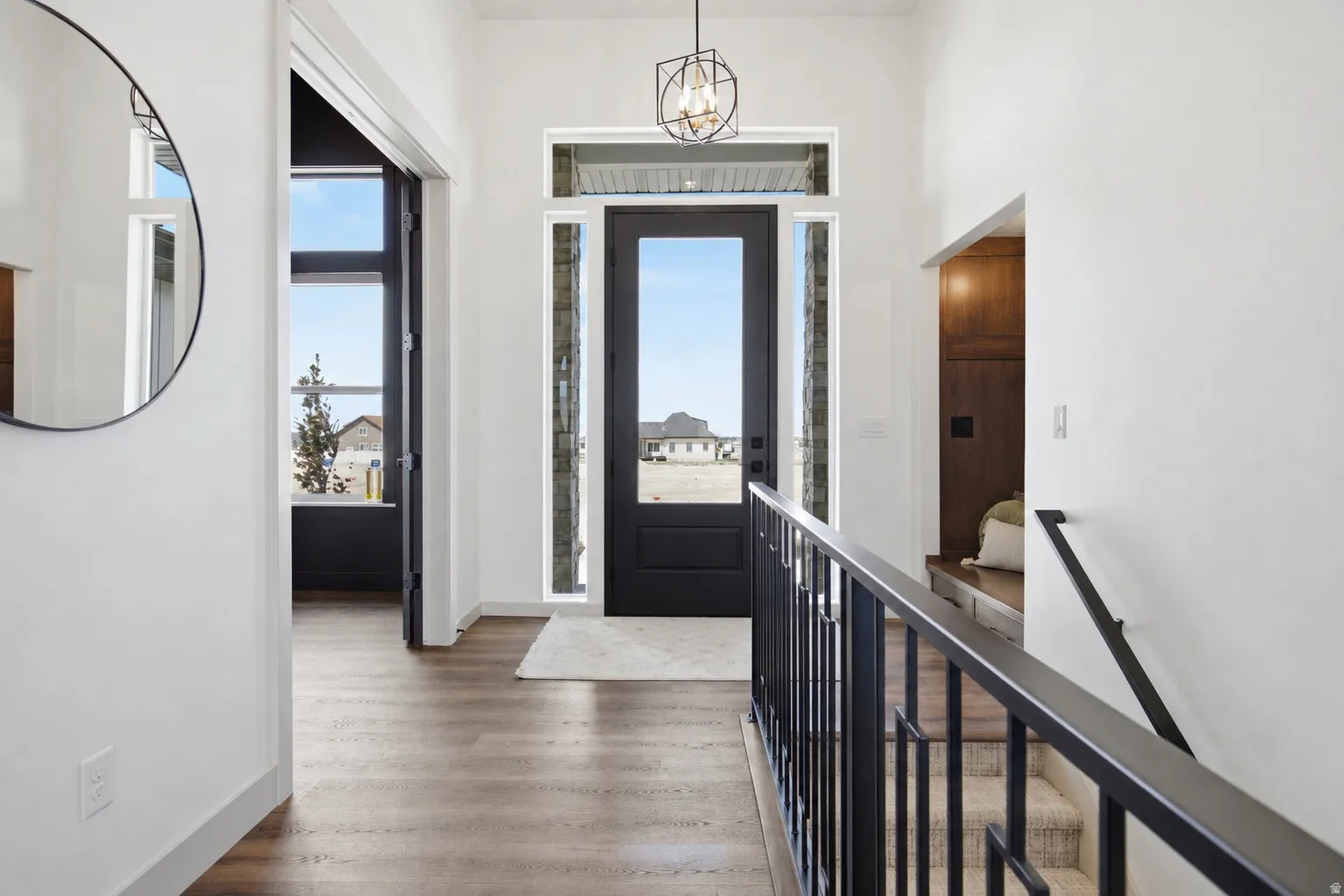 Entryway featuring a black door with sidelight windows, overhead transom window, and a geometric pendant light fixture