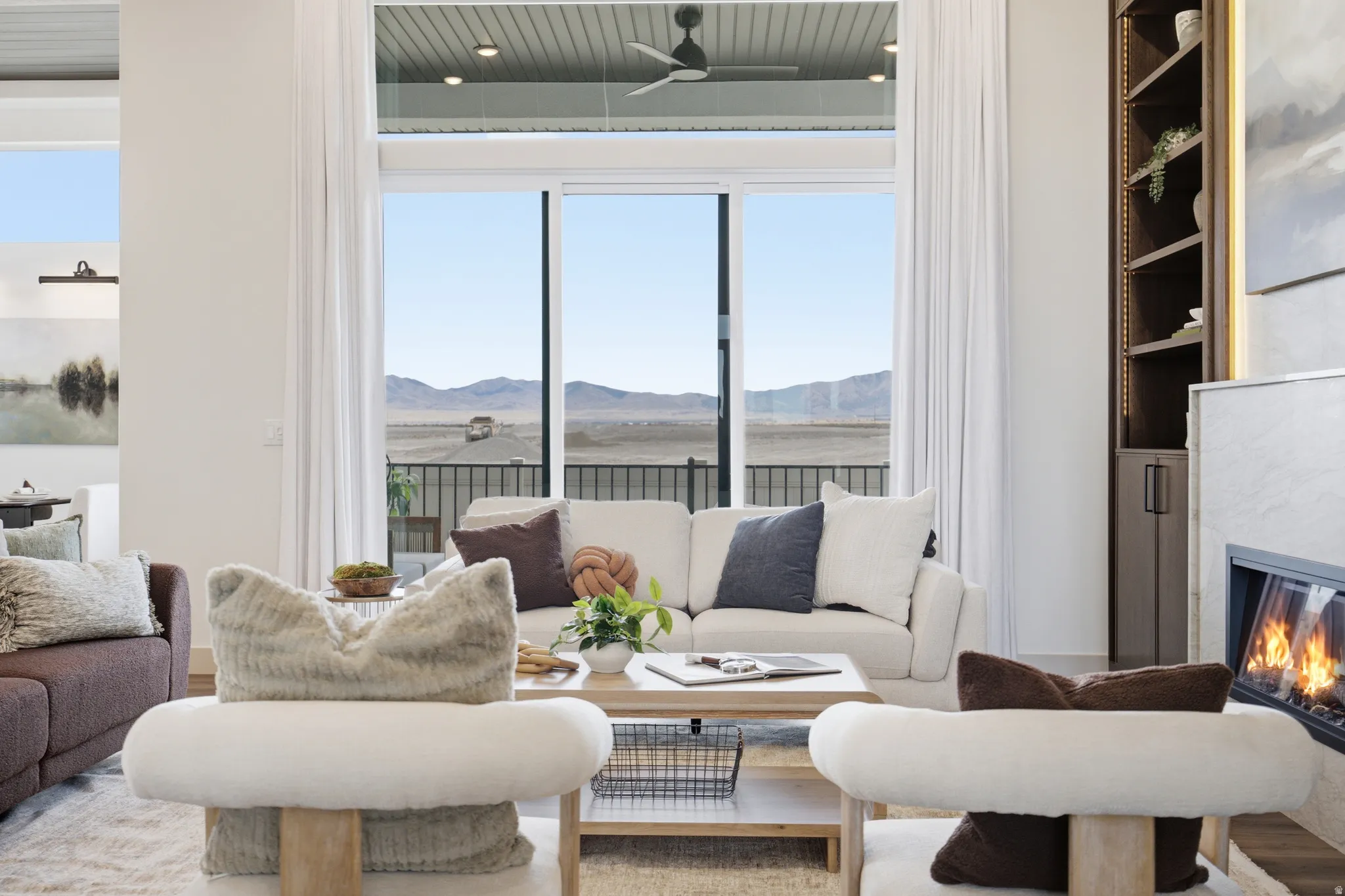 Spacious living area featuring floor-to-ceiling sliding glass doors, a built-in fireplace with a stone surround, recessed lighting, and a custom built-in shelving unit with integrated lighting