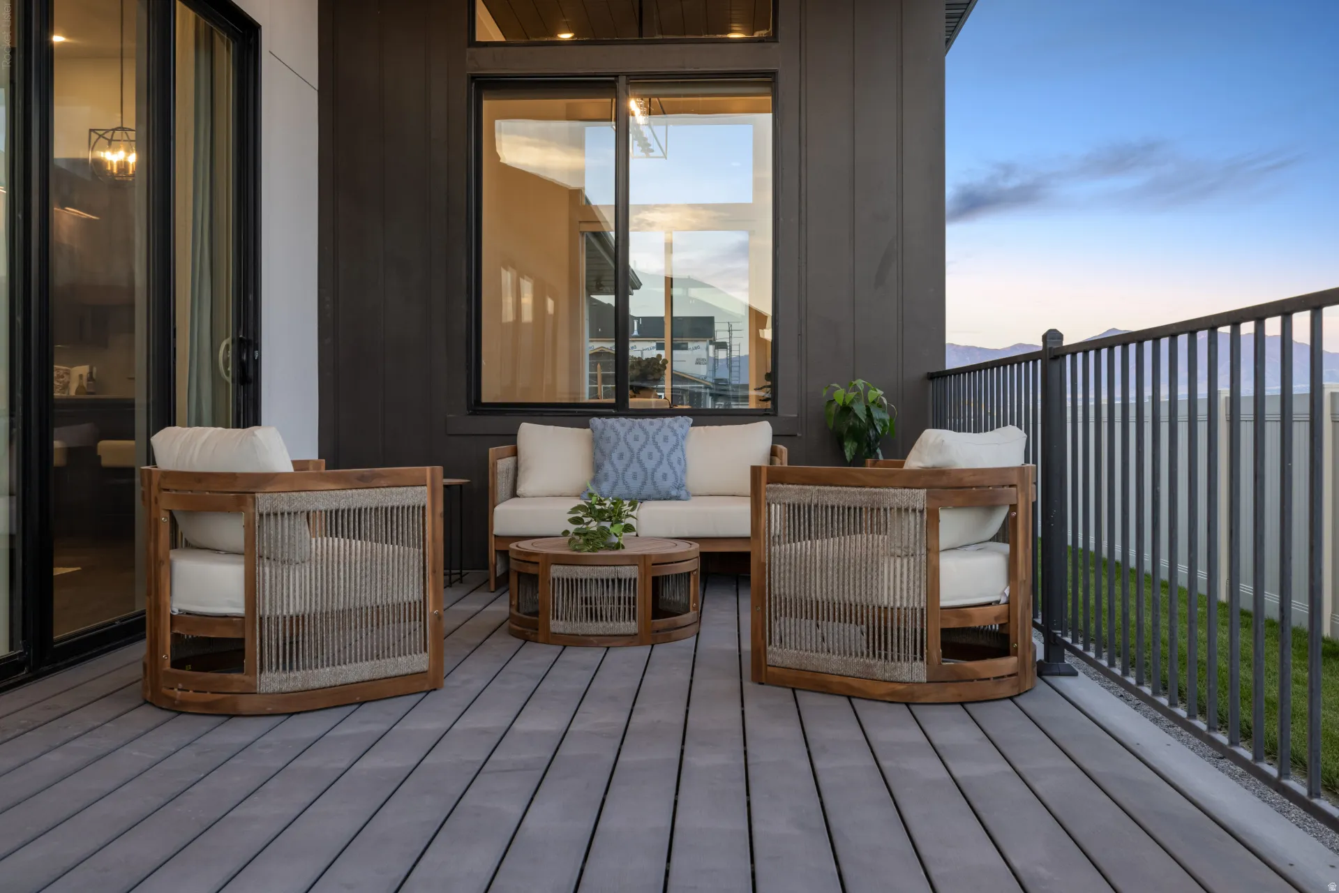 Outdoor patio featuring a gray composite deck, dark vertical siding, and a black metal railing