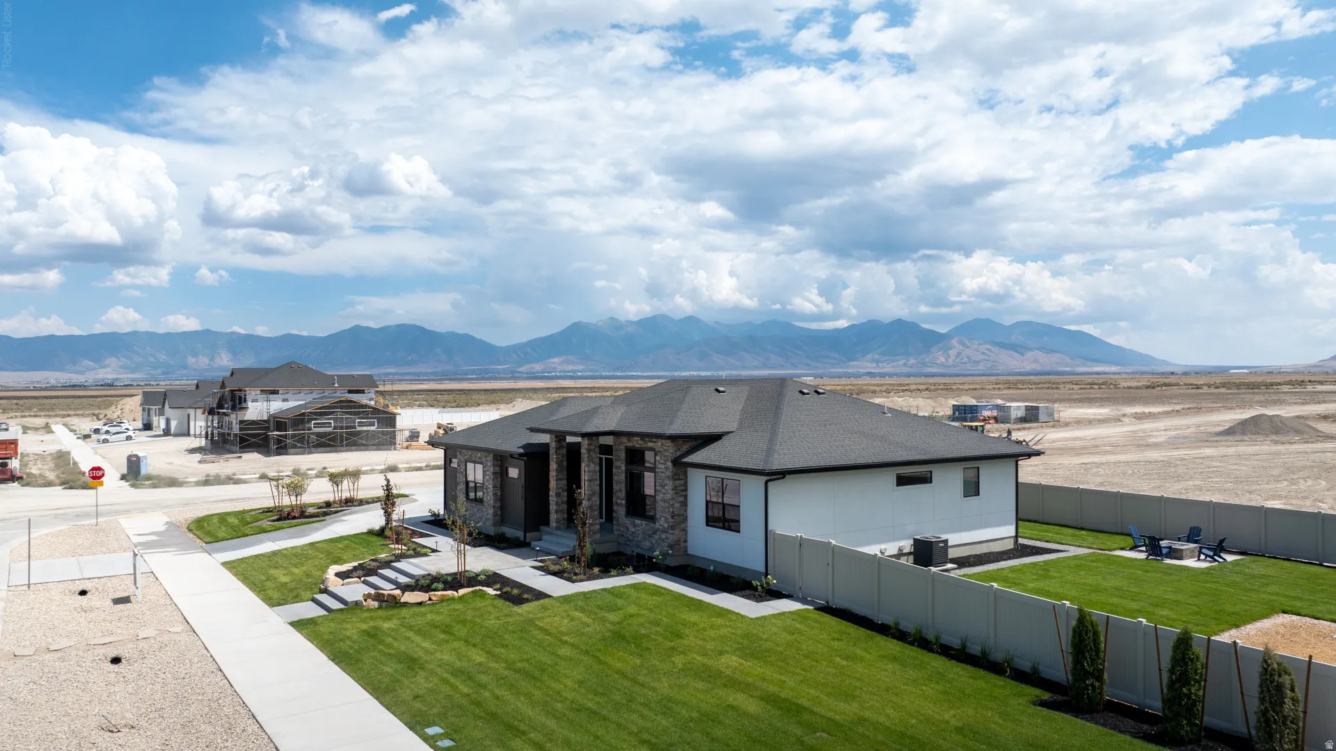 Contemporary ranch-style residence featuring a dark shingle roof, stone and stucco exterior, and a manicured front lawn