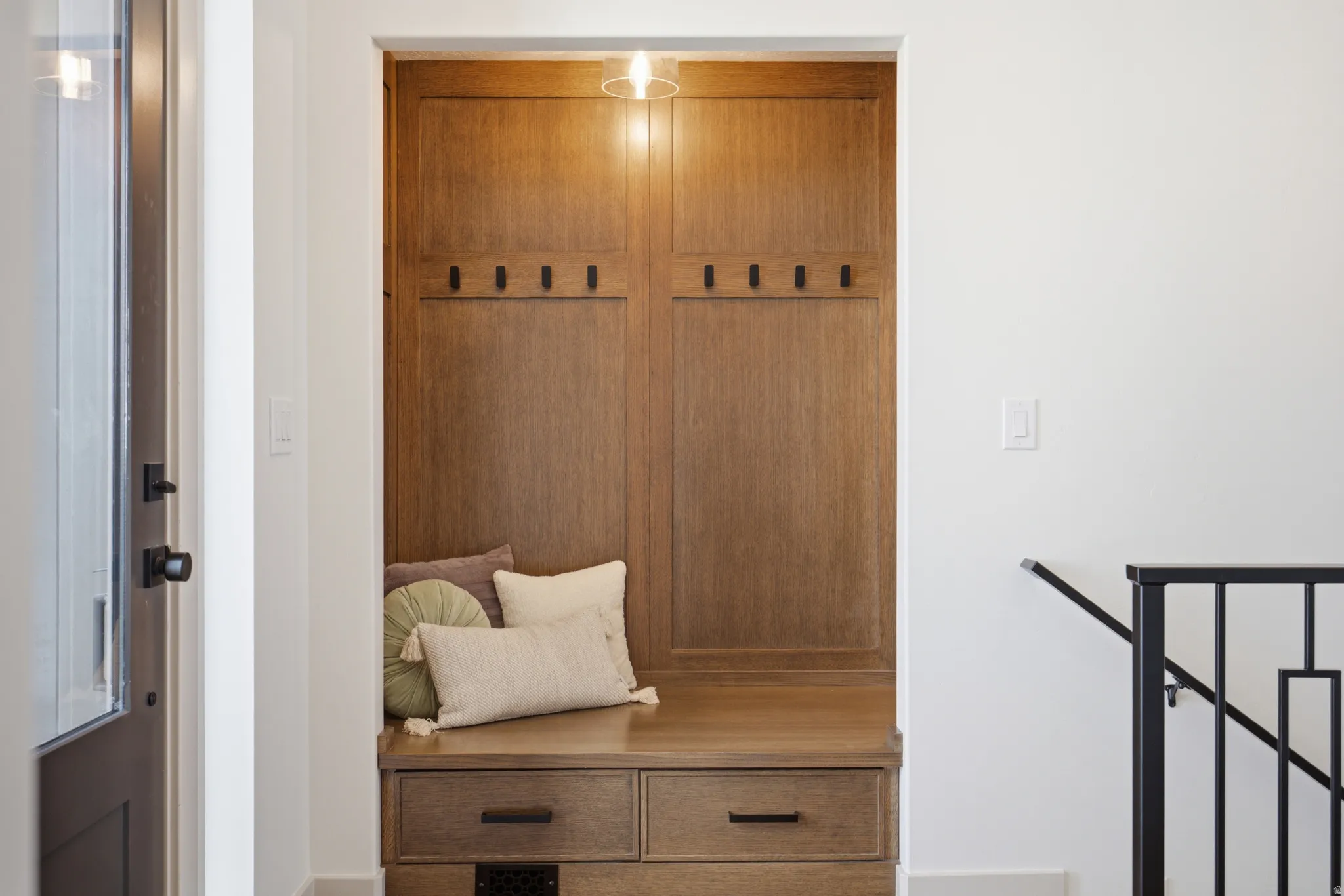 Built-in wood-finish bench and storage unit featuring integrated coat hooks and drawer storage