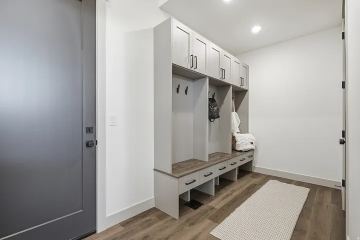 Entryway with wood-finish flooring featuring a custom built-in bench with integrated storage and overhead cabinetry