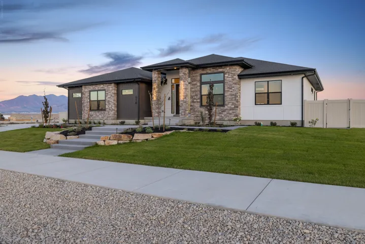 Contemporary-style residence featuring a stone and stucco exterior with dark trim windows