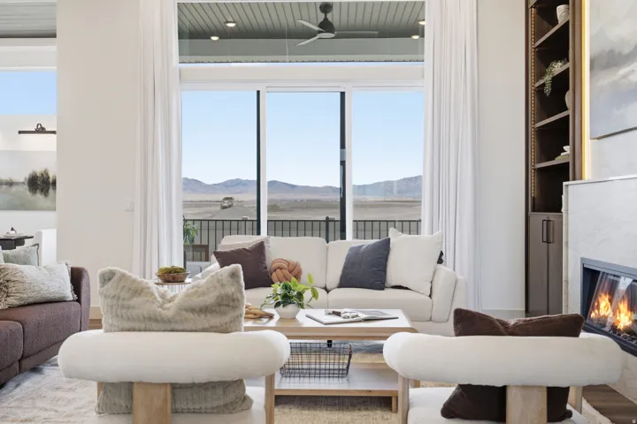 Spacious living area featuring floor-to-ceiling sliding glass doors, a built-in fireplace with a stone surround, recessed lighting, and a custom built-in shelving unit with integrated lighting