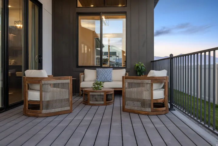 Outdoor patio featuring a gray composite deck, dark vertical siding, and a black metal railing