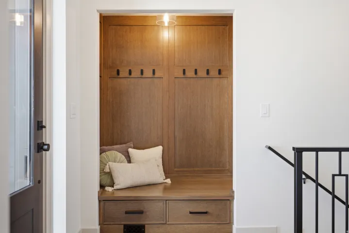 Built-in wood-finish bench and storage unit featuring integrated coat hooks and drawer storage