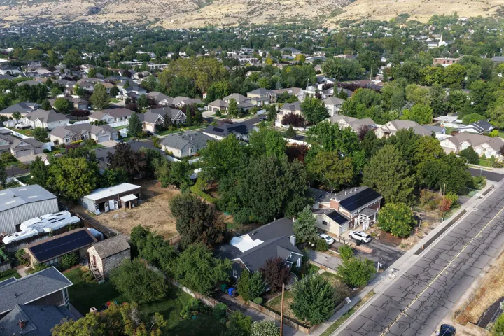 Residential neighborhood with varied rooflines and mature trees, set against a mountain backdrop