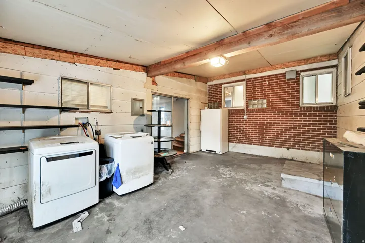 Exposed brick wall, concrete flooring, exposed wooden ceiling beams, multiple windows, built-in shelving