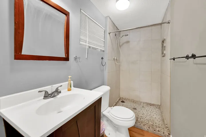 Vanity with wood-finish cabinetry, white countertop, and integrated sink
