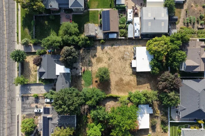 Expansive parcel with clear land, surrounding mature trees, and existing structures