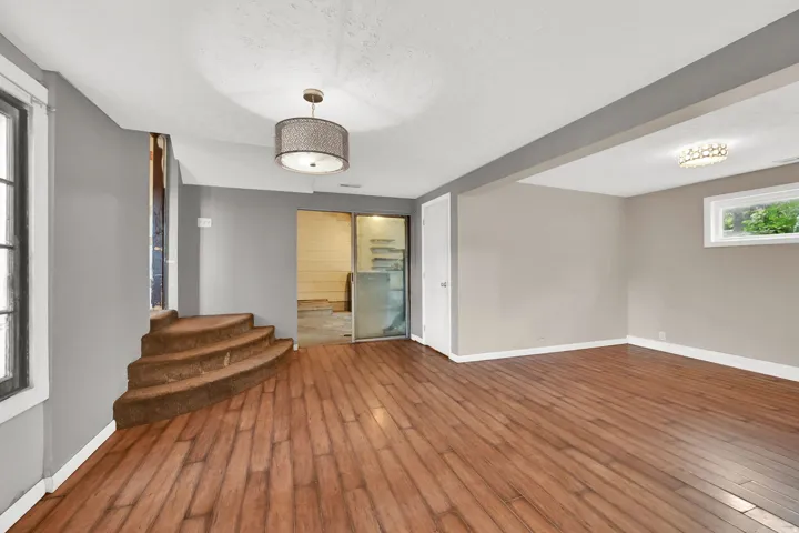 Spacious room featuring wood-finish flooring, recessed lighting, and a drum pendant light fixture