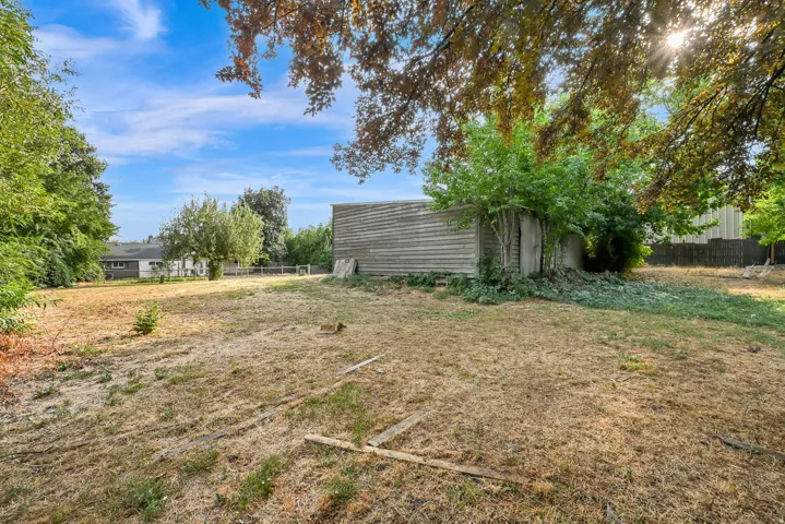 Expansive undeveloped yard with a wood-sided outbuilding