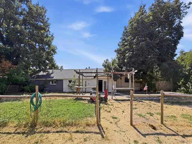 Rear exterior with a patio, wooden pergola, and mature trees